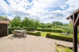 a patio with a table and chairs in a garden at Vakantiehuis Marsnil in Heers