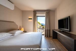 a bedroom with a bed and a tv and a window at Suite Lavanda by Villa Melograno, Pool, AC, Parking in Santa Margherita Ligure