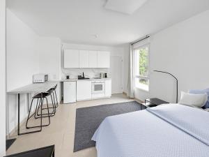 a white bedroom with a bed and a kitchen at Studio lumineux avec balcon privé in Poissy