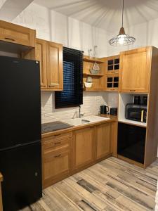 a kitchen with wooden cabinets and a black refrigerator at Spiti Skiathos town in Skiathos