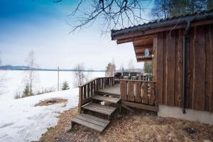 a wooden cabin with a porch with snow on the ground at Hagali by Norgesbooking - cabin by the lake Næra, close to Sjusjøen in Ringsaker