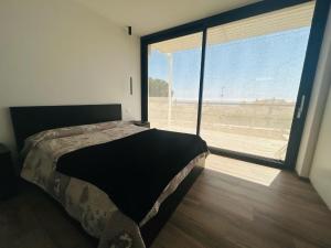 a bedroom with a bed and a large window at La casa dell'orto in Imperia