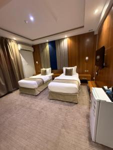 a hotel room with two beds and a television at الاتحاد الذهبية للشقق المخدومة 1 in Al Hofuf