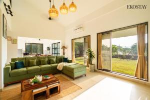 a living room with a green couch and a table at EKOSTAY - White Lotus in Karjat