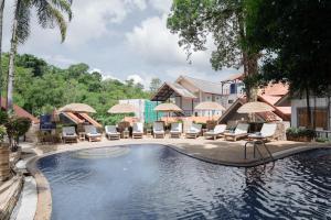 a pool at a resort with chairs and umbrellas at Club Bamboo Boutique Patong Beach Resort in Patong Beach