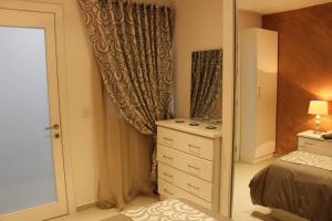 una camera con letto, cassettiera e specchio di St. Elmo Apartments a La Valletta