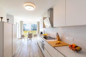 a kitchen with white cabinets and a bowl of fruit on the counter at Terrassenwohnung "Haffromantik" in Garz