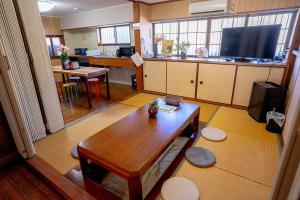 a living room with a wooden table and a kitchen at KUMANO家-OHGi- in Shingū