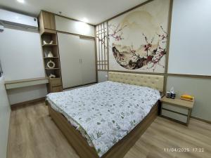 a bedroom with a bed and a painting on the wall at Nhà Nắng Vàng in Hai Phong