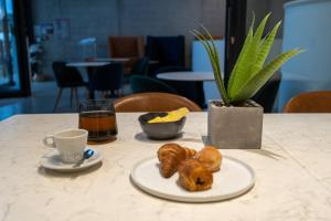 a table with a plate of pastries and a cup of coffee at Le B Complexe Hôtel in Lozanne