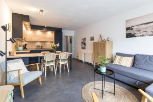 a living room with a blue couch and a kitchen at Century 2a in Wenduine