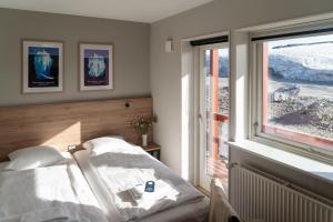 a bedroom with a bed and a window at HOTEL SØMA Ilulissat in Ilulissat
