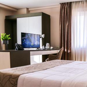 a hotel room with a bed and a desk with a computer at Doanesia Premium Hotel & Spa in Tirana