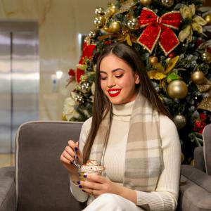 a woman sitting on a couch in front of a christmas tree at Doanesia Premium Hotel & Spa in Tirana