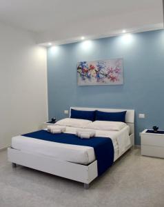 una camera da letto con un letto grande con una parete blu di B&B La CYCAS a San Vito lo Capo