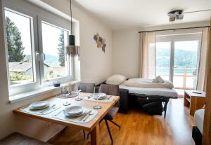 a room with a table and a bed with windows at Ferienwohnung Quehenberger in Millstatt
