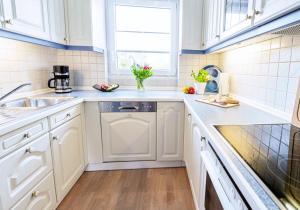 a kitchen with white cabinets and a sink at Haus Sonneneck 1 in Bad Zwischenahn