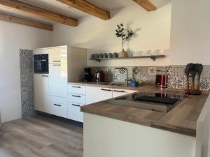 een keuken met witte kasten en een aanrechtblad bij Haus Mariechen 5-Sterne-DTV-Ferienwohnung in der Nähe zum Silbersee mit Balkon & Sauna in Frielendorf