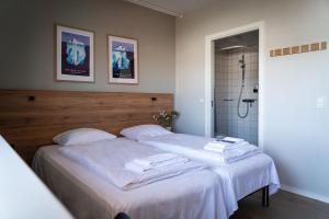 two twin beds in a room with a shower at HOTEL SØMA Ilulissat in Ilulissat