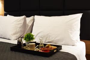 bandeja de comida en una cama con almohadas blancas en Lavish Living Suite Heraklion Crete, en Kato Gouves