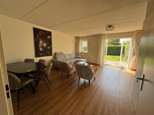 a living room with a couch and a table and chairs at Vakantiehuis Strand ,water,met infraroodsauna in Breskens