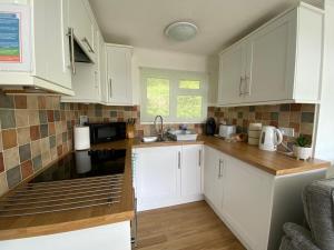 a kitchen with white cabinets and a sink at Chalet 8 The Woodlands in Tywyn