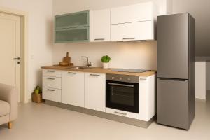 a kitchen with white cabinets and a black refrigerator at Apartmaji ŽIVA in Blato