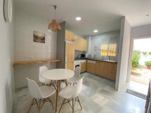 eine Küche mit einem weißen Tisch und weißen Stühlen in der Unterkunft Casa Lotte, centro histórico,AC, garaje, wifi in Sanlúcar de Barrameda