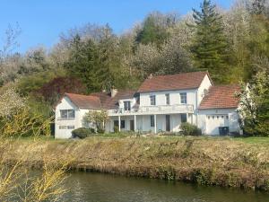 a large white house on a hill next to a river at Le Moulin de Frise in Frise