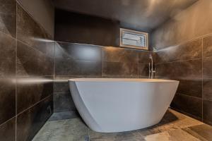 a bath tub in a bathroom with brown tiles at Palima28 in Sankt Johann in Tirol +9 photos