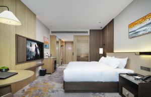 a hotel room with a large bed and a desk at Merlinhod Hotel Hejin Fengyuan in Hejin