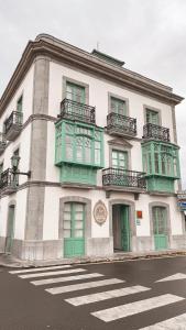 ein Gebäude mit grünen Türen und Fenstern an einer Straße in der Unterkunft Apartamentos La Colonia de Muros in Muros de Nalón
