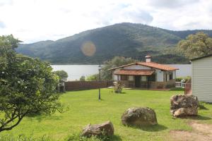 a house in a yard with rocks in the grass at Encinar del Abuelo in Casas del Castañar