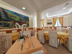 a dining room with tables and white chairs and a painting at Hotel Pace in San Giovanni Rotondo