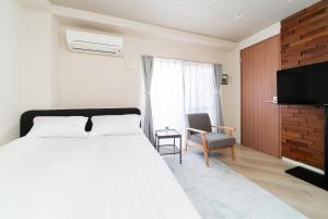 a bedroom with a bed and a chair and a television at Luce Ikebukuro - Cozy APT Stay in Ikebukuro Tokyo, with Direct Access to Shinjuku & Shibuya in Tokyo