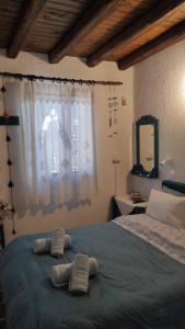 zwei Handtücher auf einem Bett vor einem Fenster in der Unterkunft Chrysa's cottage house in Karystos