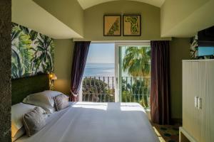 a bedroom with a bed and a large window at Hotel Villa Carlotta in Taormina