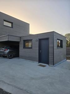a house with a garage with a car parked outside at Chambre Cosy Indépendante aux pieds des dunes in Merlimont