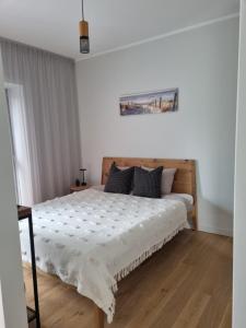 a bedroom with a large bed with a wooden floor at Albatross Green Apartment in Ķesterciems