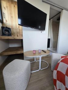 a living room with a tv and two chairs and a table at Chambre Cosy Indépendante aux pieds des dunes in Merlimont +2 photos