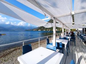 a restaurant with tables and chairs and a view of the water at Casa Bianca, Vista unica sul lago di Como in Dervio