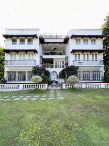 a large white building with a yard in front of it at MiraNamin Nest LIRYO and LANTANA Residence in Unique Historic Home - Garden, Rooftop, Private Kitchen in Manila