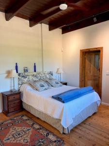 Un dormitorio con una cama grande y suelo de madera. en Sevilo Farmhouse, en Stellenbosch