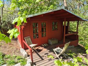 a red cabin with a chair on a deck at Glampinghütte Georgenthal in Georgenthal