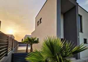 a building with palm trees in front of it at Vila OASIS - Zadar, Vrsi in Vrsi