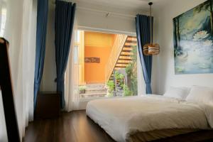 a bedroom with a bed and a window with blue curtains at Michelia Valley Hotel in Da Lat +87 photos