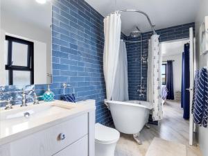 a blue tiled bathroom with a tub and a toilet at Ocean Mist in Carna +27 photos