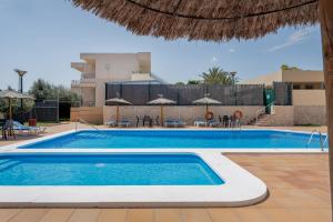 a swimming pool with chairs and umbrellas next to a building at Hospedium Hotel Abril in San Juan de Alicante