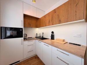 a kitchen with white cabinets and a wooden counter top at Harrachov apartment - Moderní horský apartmán v Harrachově pro 2-4 osoby, parkování, lyžárna, kolárna in Harrachov