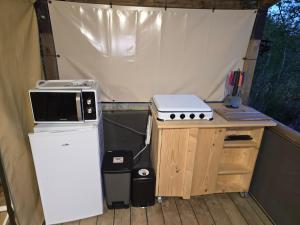 a stove and a refrigerator in a tent at Clos des Monts Tente Lodge Safari R in Saint-Martin-des-Besaces